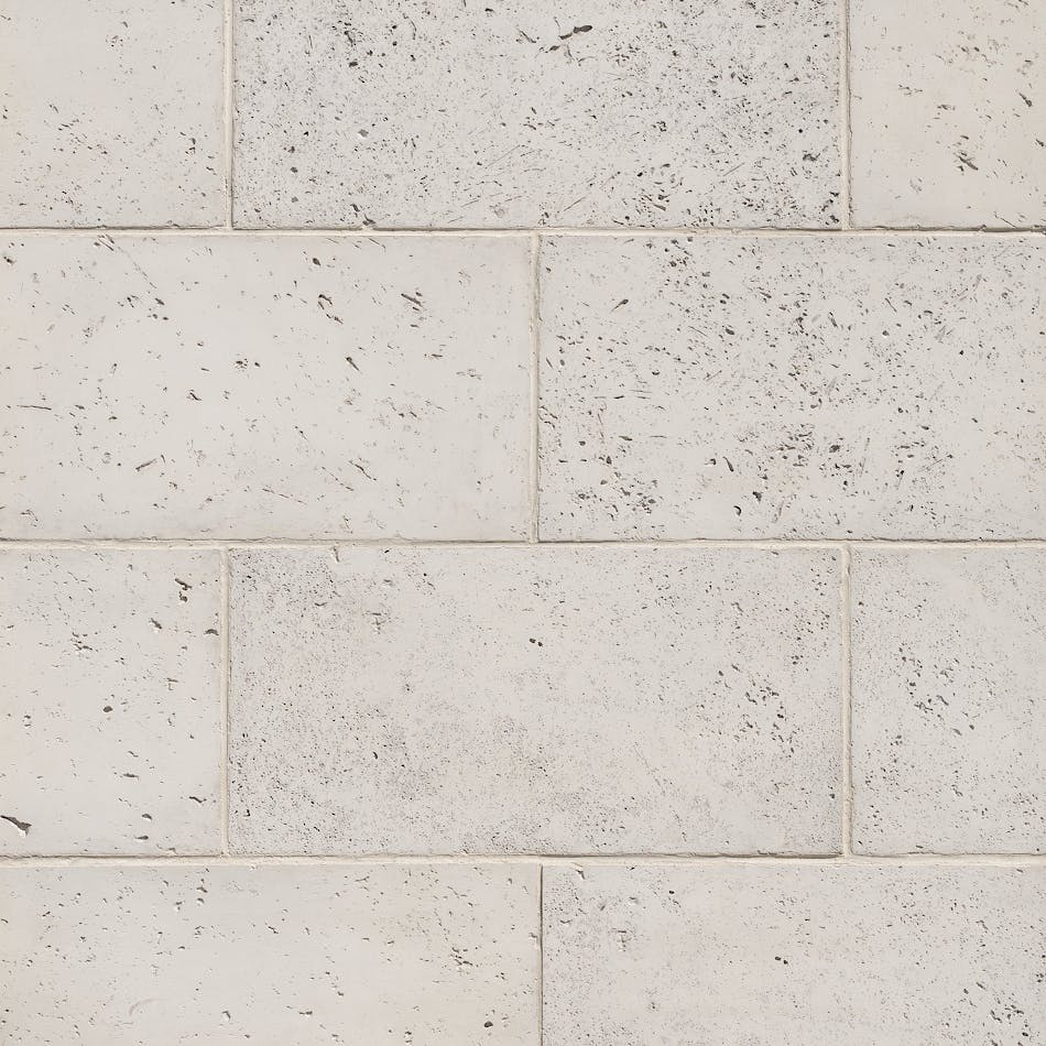Close-up of symmetrically placed white stone veneer blocks with dark specks.