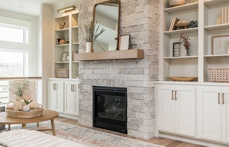 Living room fireplace treated with a modern stacked ledge stone, flanked by matching wood cabinets.