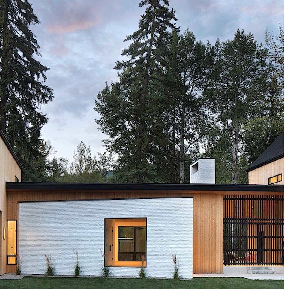 Exterior of home with vertical lap siding and a prominent white brick veneer accent wall with a window.