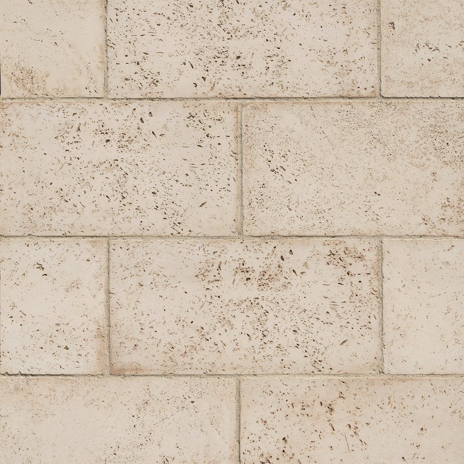 Close-up of symmetrically placed off-white stone veneer blocks with dark specks.