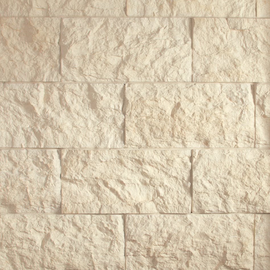 A creamy-colored stone veneer wall with split-face texture and rectangular shape.