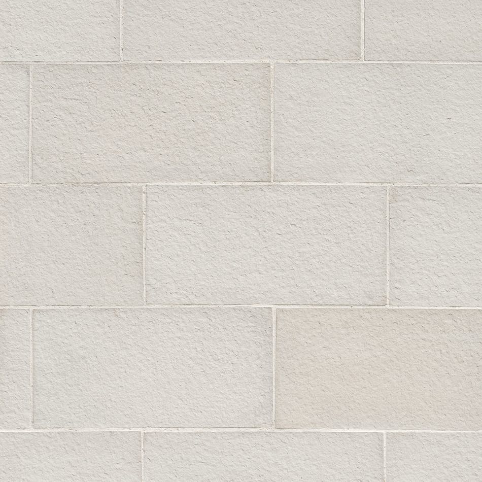 A wall with large, square-edged rectangular stone veneer with a soft texture in the shade Bright Horizon.