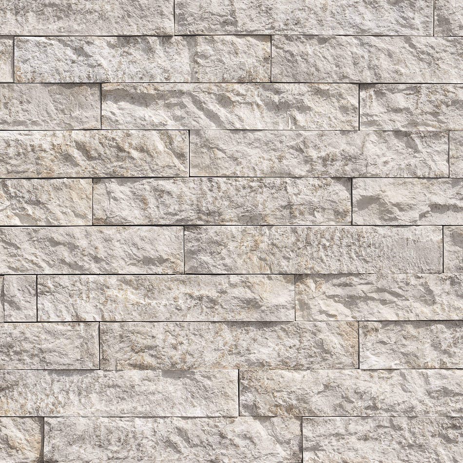 A stone veneer wall with uniformly ledge-shaped, rectangular stone with a split-faced surface in the shade Morning Light.