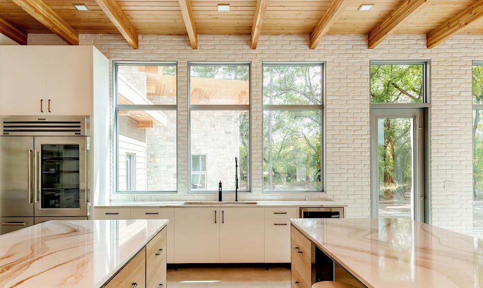 Kitchen interior with accent wall of white brick veneer studded with oversized windows.