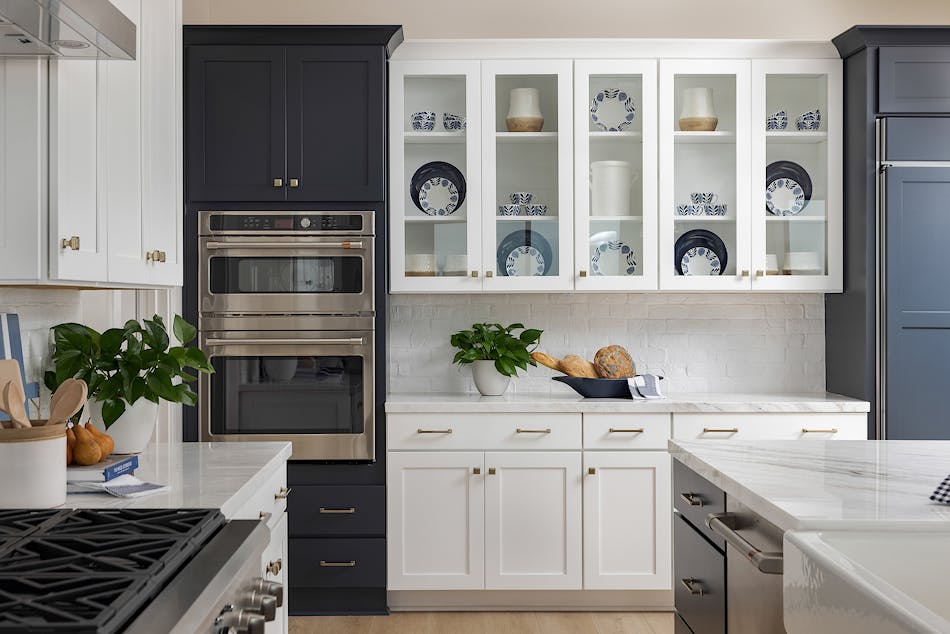 Modern kitchen with masonry veneer backsplash, white cabinets, and dark stainless steel appliances.