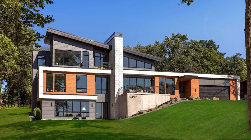 Expansive modern home featuring extensive glass, wood, concrete and limestone fireplace chimney.