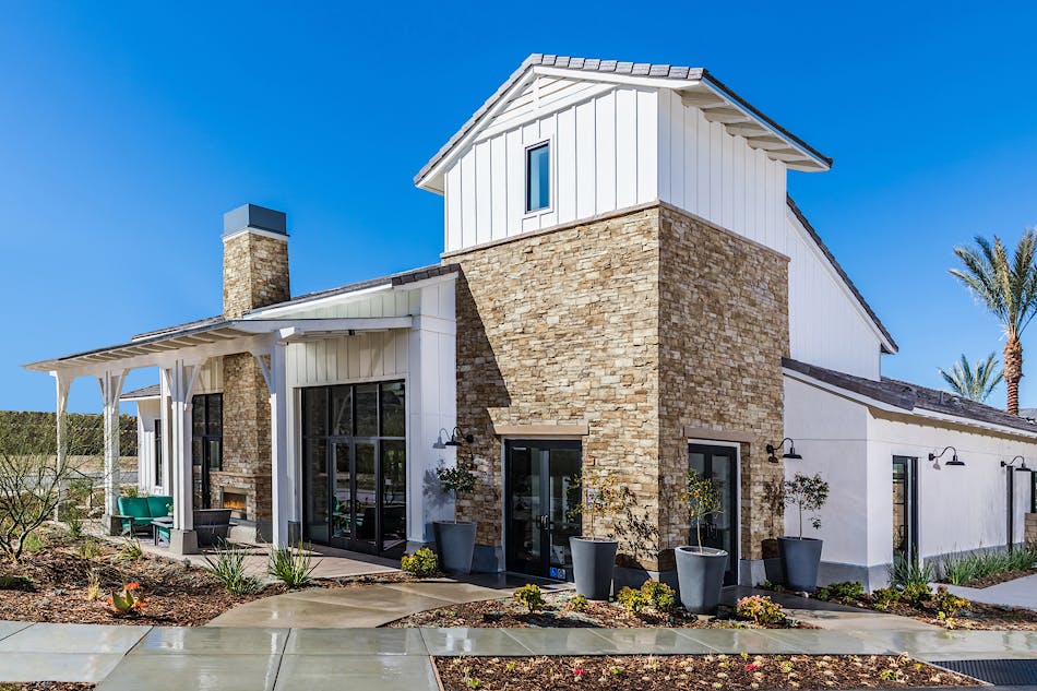 A farmhouse-style home with stone veneer siding accents. The home is white with black accents.