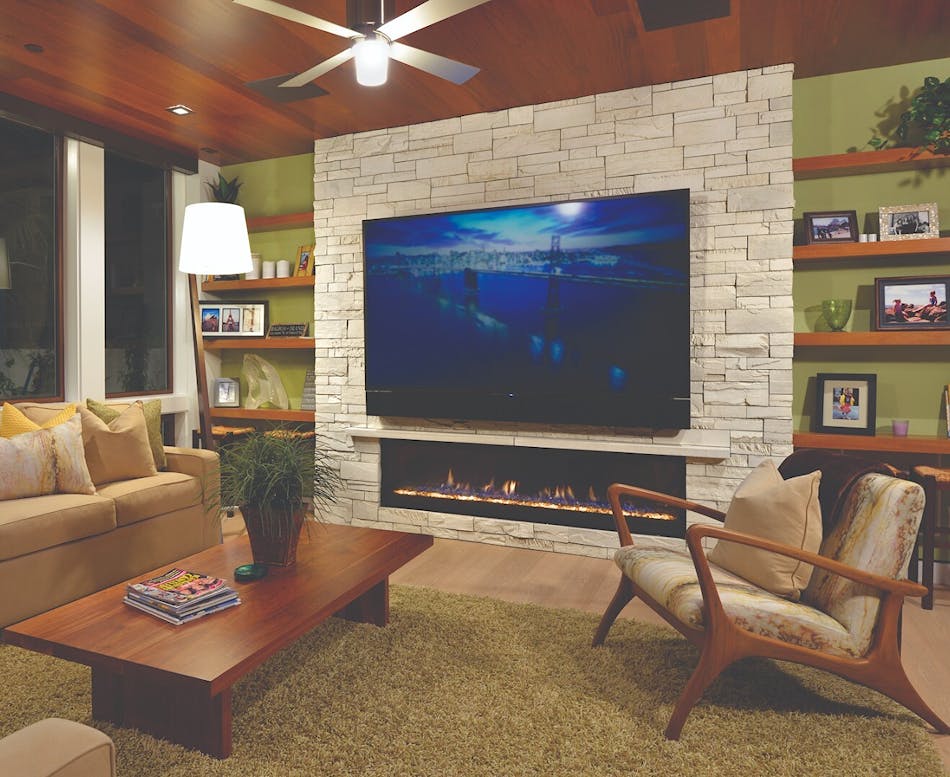 This cream-color stone veneer fireplace has a large television mounted to it. There is a beige couch, a wooden coffee table and a wooden chair in the living room.