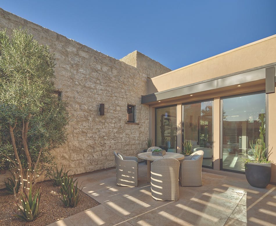 This exterior patio area features a circular table with four chairs and a stone veneer accent wall.