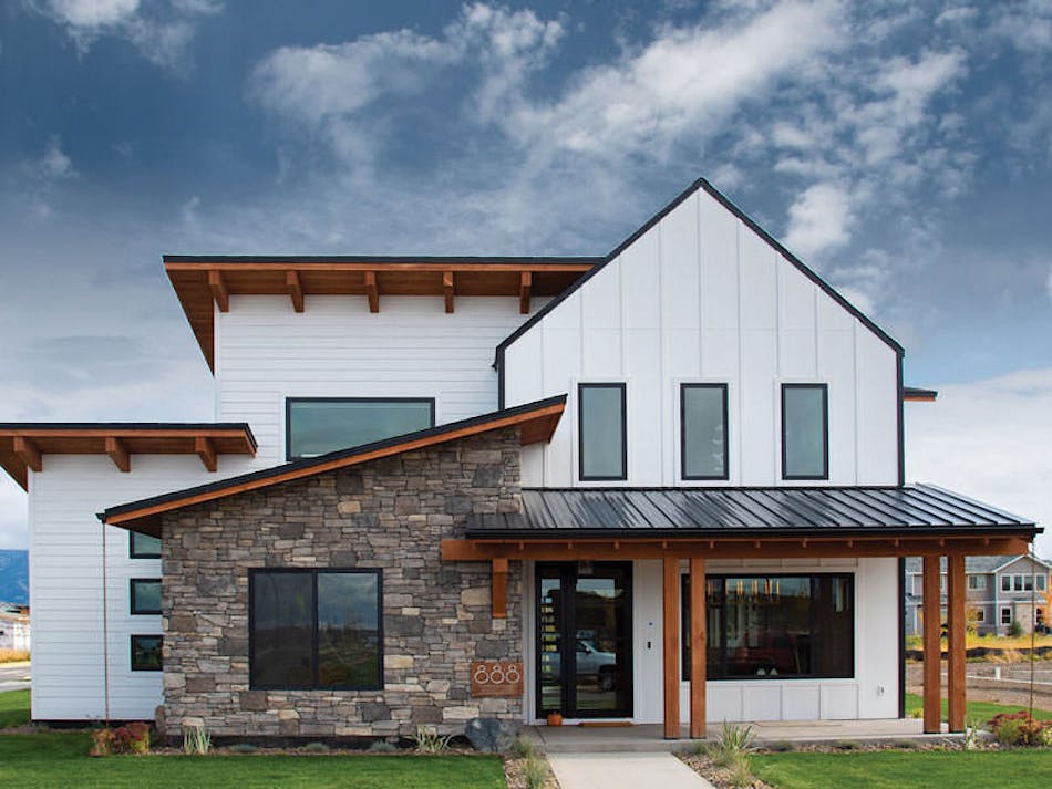 A farmhouse-style home with a stone accent wall. The home is white with black and brown accents.