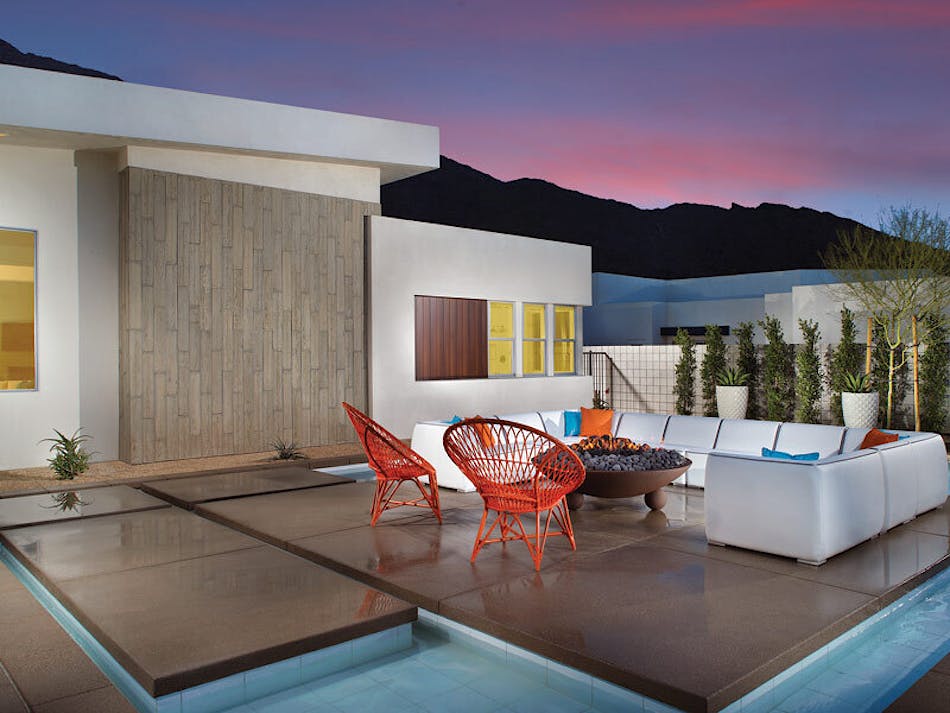A modern backyard patio of a home. The outdoor patio furniture sits on top of panels over a pool area.