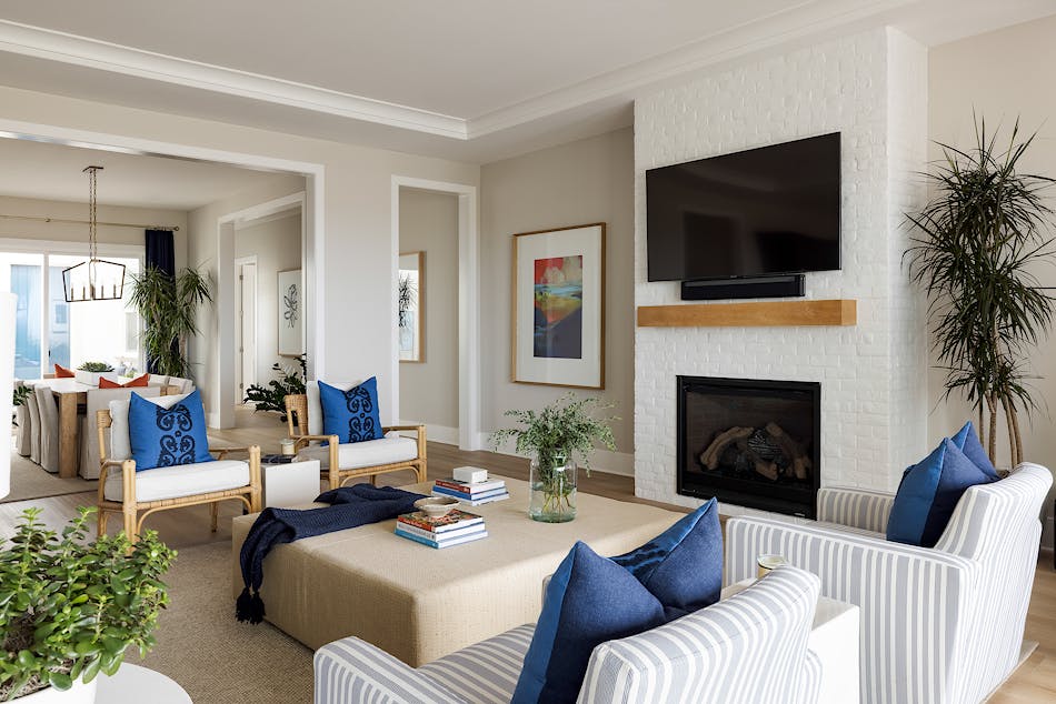 A blue and white colored living room. The room has two sets of chairs on either side of a white brick fireplace.